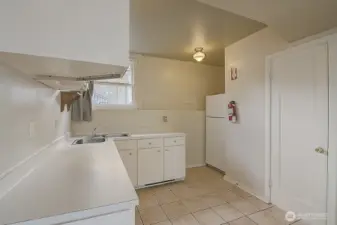 Lower unit kitchenette, view 1, showcasing cabinets, sink, and refrigerator.