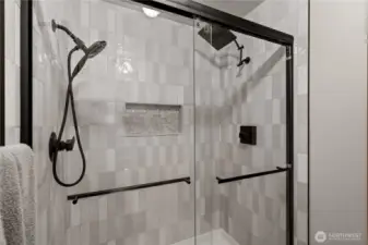 Beautiful shower tiling features a built-in tiled shelf, keeping the shower floor clutter-free and enhancing both style and functionality.
