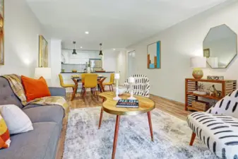 Living room and dining room off of the kitchen with light pouring in from sliding door to balcony.