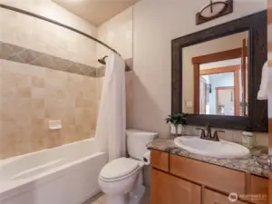 View of main level powder room/full bath w/ granite countertops and European tile.