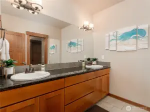 View of lower level bathroom suite w/ double vanities, linen closet and European tiled shower.