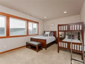 View of lower level bedroom 3 w/ oversized windows, double closets and a queen bed plus full size bunk beds.