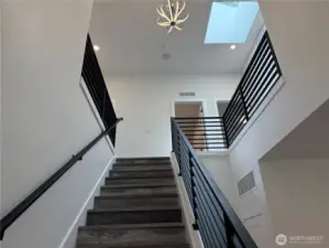 Dramatic Vaulted Ceiling with Skylight and Gorgeous Modern Chandelier. Look how Beautiful the Staircase is with the Planked Stairs and Modern Black Coated Metal Hand Railing too.
