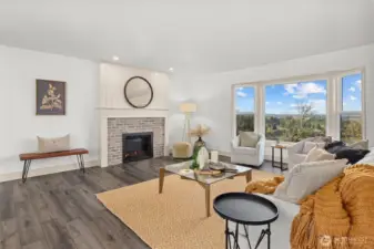Welcoming main floor living room with brick fireplace and large bay window, perfect for taking in the view!