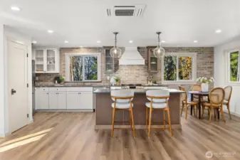 Custom kitchen that beautifully coordinates with main house featuring same honed granite countertops, brick backsplash, LG stainless steel appliance package and pendent lighting.
