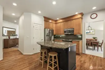 The informal areas are one contiguous space and feature an updated kitchen with maple cabinets with soft close drawers and doors, slab granite counters, an island with seating, stainless steel appliances including a gas range and a walk-in pantry.