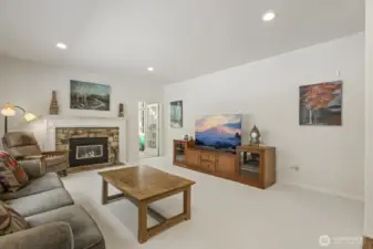 The informal gathering room features a stone surround gas fireplace and sliding door to the deck.