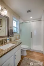 Primary bath features walk in shower with subway tiles and heavy opaque glass doors