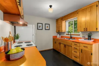 Retro circa 1964 vibe kitchen with fun orange Formica counters and dark LVP flooring.