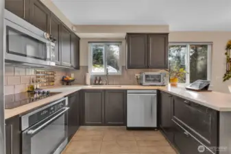 The kitchen features stunning quartz countertops, a stylish tile backsplash, & sleek SS appliances.