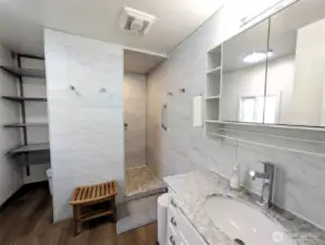 Primary bathroom with walk-in tiled shower and shelving