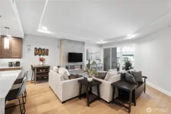 Comfort without compromise.  The living area centers around a sleek electric fireplace and a cozy seating arrangement designed for connection and calm. Soft textures, warm wood tones, and 9-foot ceilings give the space a grounded, airy feel. Slide open the glass doors and let the sea breeze remind you—you’re living just steps from the Sound.