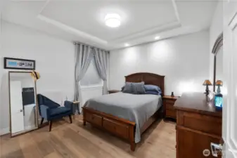 A peaceful retreat with timeless charm.  This spacious primary bedroom features crown molding, warm hardwoods, and recessed lighting that creates a soft, relaxing glow. With room for a reading corner and full-sized furnishings, it’s a restful escape from the energy of the waterfront—quiet, elegant, and perfectly private.