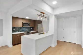 Sharp design in shared spaces.  Even the shared amenities echo the attention to detail found throughout the building. This designer kitchen features warm wood cabinetry, a statement backsplash, and brass fixtures—all part of a cohesive, elevated community experience. Entertain, connect, or just cook up something special in style.