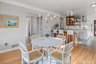 Light-filled dining area with refinished hardwood floors and crisp crown moulding flows seamlessly into the updated kitchen. Modern pendant lighting, a sleek chandelier, and open sightlines create the perfect setting for everyday meals and entertaining.