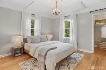 Serene primary bedroom with cove ceiling trim detail and abundant natural light.