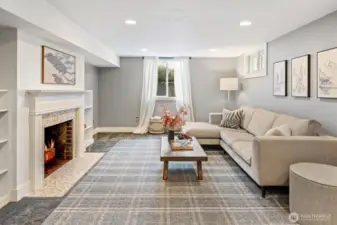 Spacious lower-level family room with wood-burning fireplace, built-ins, and natural light—ideal for media and play. Doubles as a private living room retreat for visiting guests.