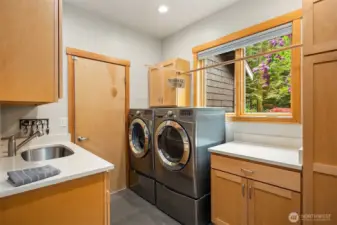 The spacious utility/mudroom features a utility sink, and abundance of cabinet space and folding table.