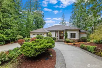 Front exterior with landscaped yard, curved driveway, and attached garage