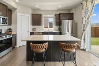 Kitchen features stainless steel appliances, quartz countertops & pantry closet.