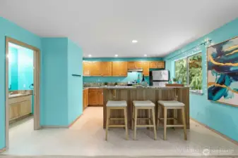 Open-concept downstairs living space with kitchen and cozy lounge area. (Virtually Staged )