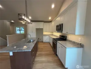 Open concept, two tone cabinetry, granite counters, Cabinets finished with crown molding and under mount lighting