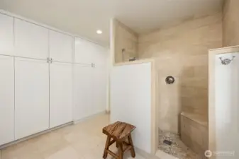 A wall of closet space and spacious shower with bench seat grace the bathroom.