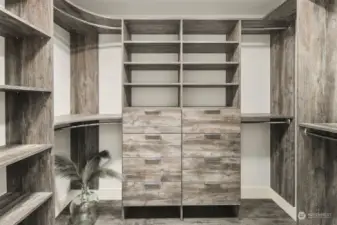 Primary walk-in with custom closet system of drawers, shelves and hanging space.