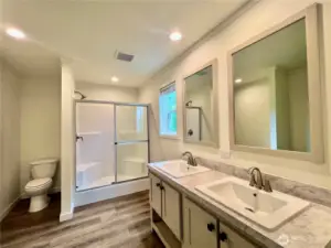 Mater bath features double sinks and walk in shower with built in seating.