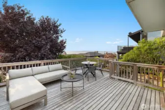 The expansive cedar deck extends the living space outdoors, offering room for both lounging and dining. Surrounded by mature landscaping, it provides privacy while opening to views of Shilshole Bay.