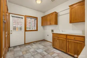 Big laundry room with lots of cabinets, storage closet and built-in ironing board.  Door offers access to side of home.