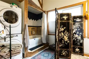 Full-size stackable laundry, tile floors, and a deep soaking tub in this generously sized bathroom