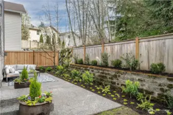 Private outdoor space backing to the forest offers the perfect backdrop for your outdoor entertainment space. The patio is surrounded by Hydrangeas, climbing jasmine on the fence, daphne for summer fragrance, and mosses and ferns for ground cover interest. It's an inviting space meant for relaxation.
