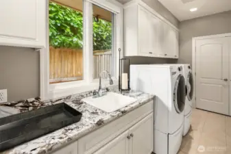 Massive laundry area just off the 3 car garage with slab counters, sink and Whirlpool washer and dryer.