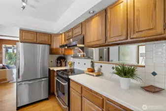 A closer view of the kitchen, displaying solid-surface counters, tile backsplashes, and stainless steel appliances.