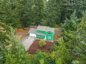 Aerial view of 513 Hidden Forest Dr SE showcasing its private, wooded setting. Surrounded by towering evergreens and located on a generous lot, this home offers a peaceful retreat while still being close to local conveniences. Fully fenced backyard and mature natural landscaping provide exceptional privacy and Northwest charm. No HOA!