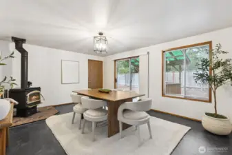 Spacious dining area enhanced by a cozy wood-burning stove, modern lighting, and warm natural textures—an inviting setting for everyday meals or gatherings leading to glass slider doors and your covered back patio.