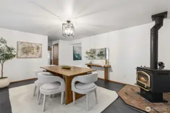 Spacious dining area enhanced by a cozy wood-burning stove, modern lighting, and warm natural textures—an inviting setting for everyday meals or gatherings.