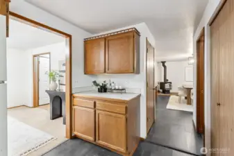 Convenient kitchen passthrough with additional cabinetry and counter space, offering an easy flow into the dining area with cozy wood stove.