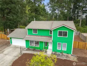 Front exterior of 513 Hidden Forest Dr SE in Olympia — a spacious two-story home tucked against a serene backdrop of mature evergreens. Features include an oversized driveway, two-car garage, fresh exterior paint, and a fully fenced side yard with wide gate access. Low-maintenance landscaping and a peaceful cul-de-sac setting create an inviting first impression. No HOA!