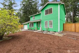 Fresh landscaping and mature evergreens frame this welcoming two-story home. The spacious front yard offers plenty of room for gardening, play, or future personal touches, while the fenced surroundings provide privacy and a peaceful natural backdrop. A charming covered entry adds to the home’s inviting presence.