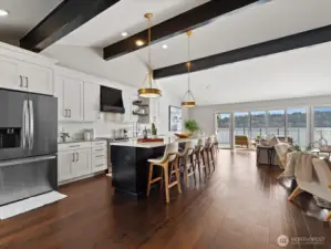 Kitchen and living area with open layout, island seating, hardwood floors, and access to waterfront deck