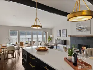 Open-concept kitchen, dining, and living area with island seating, hardwood flooring, and large windows overlooking Lake Sammamish