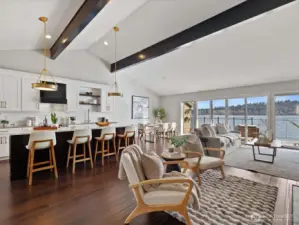 Open-concept living and kitchen area with island seating, vaulted ceilings, hardwood flooring, and access to waterfront deck