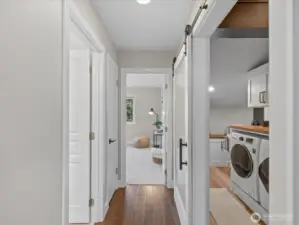 Interior hallway with hardwood flooring and adjacent laundry room with washer and dryer