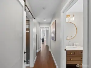 Interior hallway with hardwood flooring and access to bedrooms and bathroom
