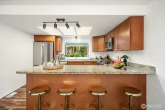 A generous breakfast bar with granite countertops and comfortable bar seating creates a casual and convenient space for everyday meals or entertaining guests. The open sight lines into the kitchen and beyond reflect the home's bright, connected layout that flows effortlessly from space to space.