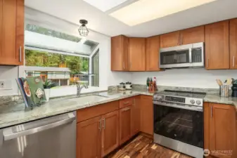 This well-appointed kitchen offers a smart and efficient layout with rich wood cabinetry, granite countertops, and a full suite of stainless steel appliances including a gas range and built-in microwave. A bright window above the sink brings in natural light and a pleasant view, making everyday tasks in this beautifully updated kitchen an absolute pleasure.