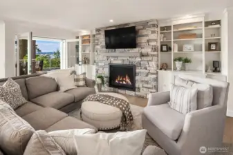 A gas fireplace, custom built-ins, and quartz cabinet tops with french doors leading to the deck.