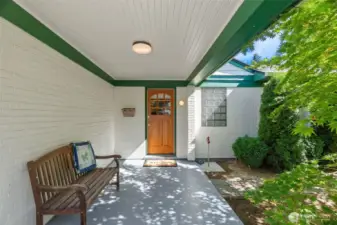 Welcoming covered porch with tongue-and-groove paneled ceiling and delightful wood-and-glass-paned door.